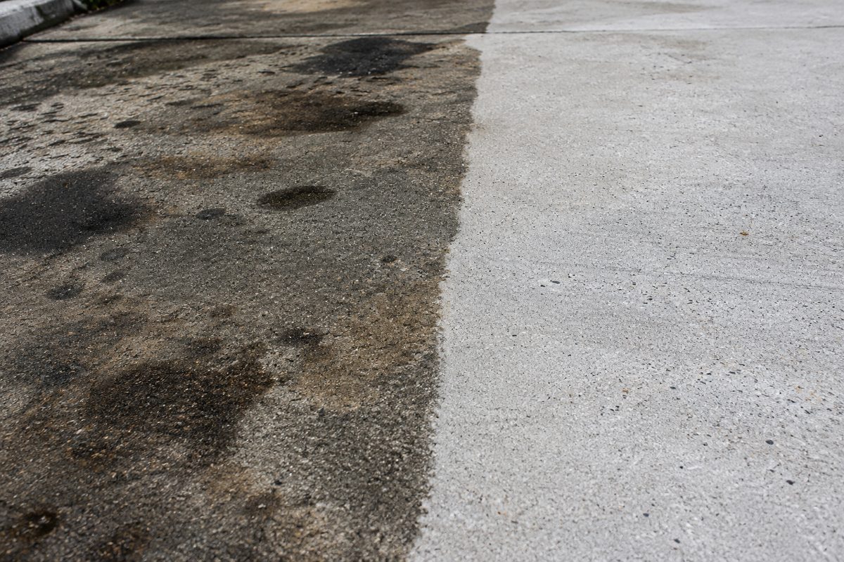 Industrial hot-water cleaning extracting grease and oil stains from warehouse concrete.